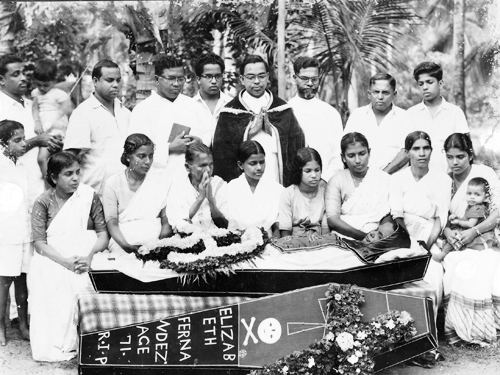 Clergy members assembled behind a floral arrangement and coffin marker for Elizabeth Fernandez