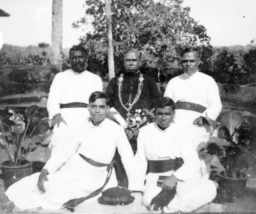 Fr. Charles M. Fernandez seated among fellow parish priests during an outdoor gathering